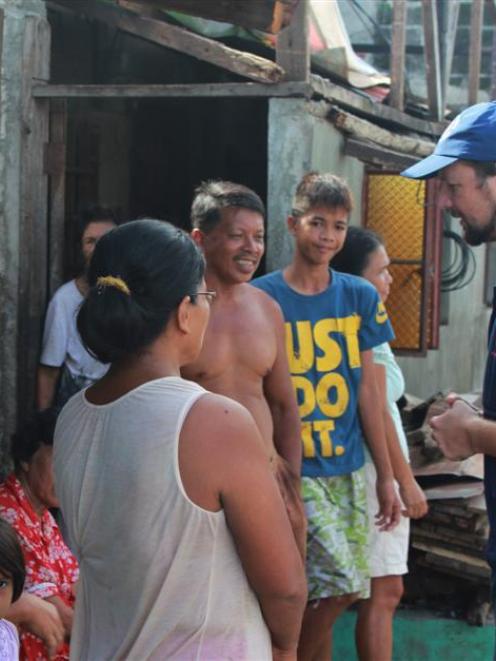 Aid agency field communication officer Andrew Robinson, of Auckland, talks to residents of Dulag,...