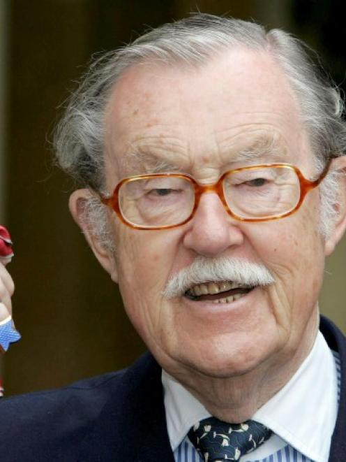 Alan Whicker holds his CBE (Commander of the Order of the British Empire) after receiving the...
