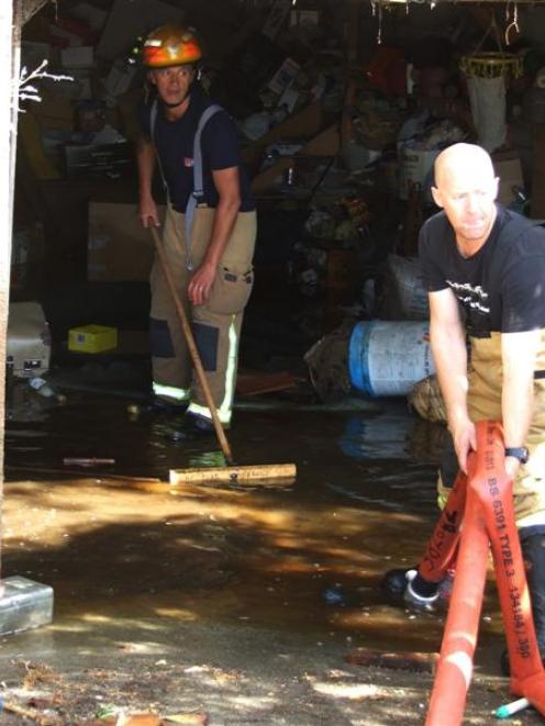 Firefighter Jason Galbraith begins clearing  water from the basement of Shirley Wright's...