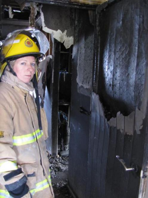 Alexandra firefighter Stacey Waldron shows how closing a door can  trap  a house fire. Photo by...