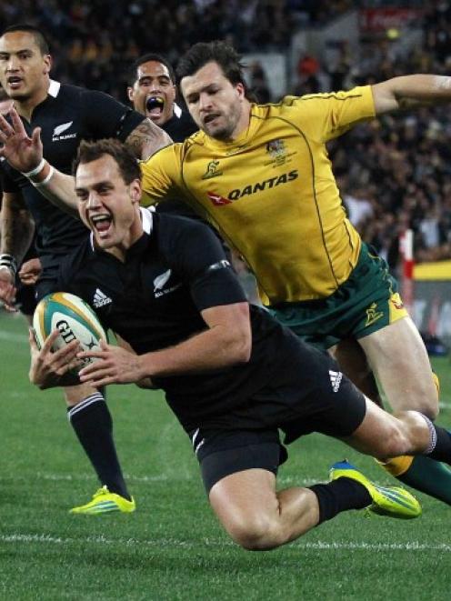 All Black fullback Israel Dagg crosses for a try despite the attentions of Wallabies winger Adam...