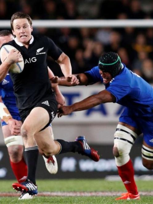 All Black winger Ben Smith avoids the tackle of French captain Thierry Dusautoir during the first...