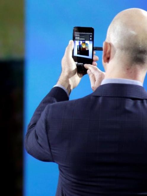 Amazon CEO Jeff Bezos demonstrates features of his company's new Fire smartphone at a news...