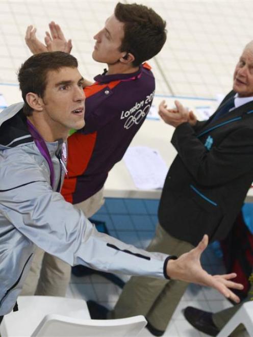 American swimmer Michael Phelps tosses his medallist bouquet to his mother in the stands after a...