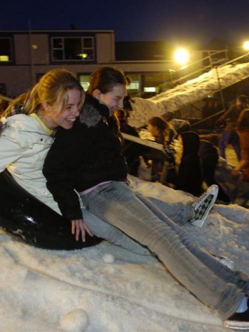 Amy Foster (15), left, and Evangeline Boyd (14) tube down a ramp at a snow party held at...