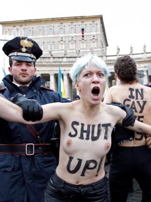 An activist from women's rights protest group Femen is restrained as Pope Benedict XVI leads his...