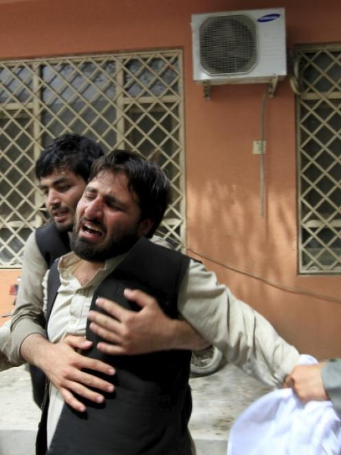 An Afghan man cries near the dead body of his brother after a suicide attack in Jalalabad. Photo...