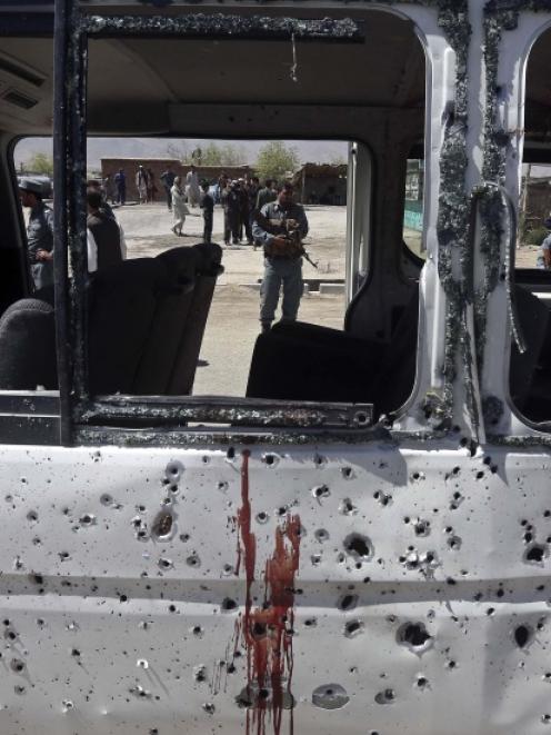 An Afghan policeman is seen through the broken windows of a vehicle after was hit by a remote...