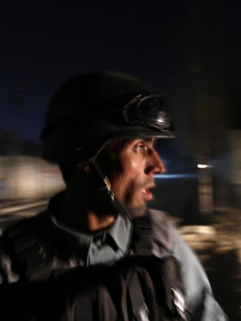 An Afghan policeman keeps watch at the site of a Taliban attack on a foreign aid workers' guest...