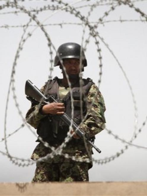 An Afghan soldier stands guard on a roof of one of the gates to Kabul's airport following a...