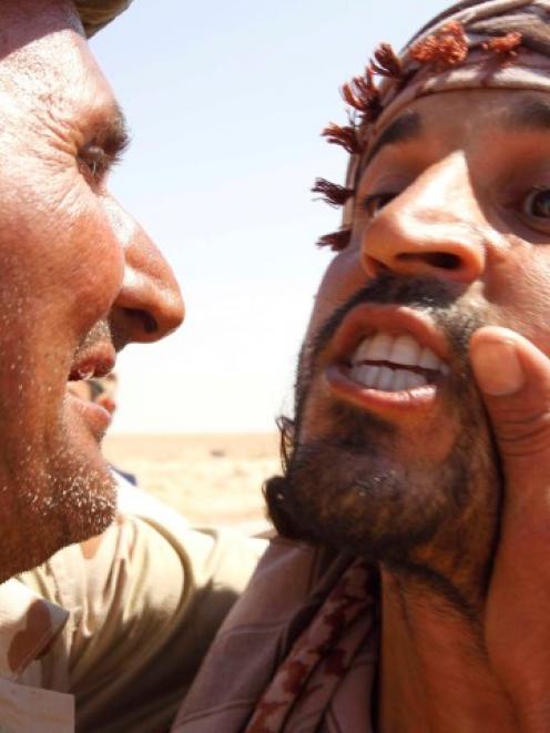 An anti-Gaddafi fighter congratules another fighter after he captured a sniper at the Bani Walid...