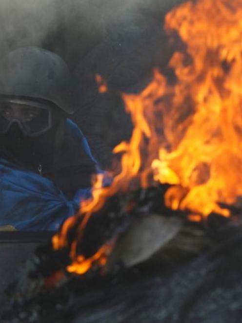 An anti-government protester rests at an open fire as temperatures reach -20degC at a barricade...