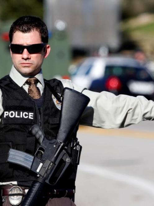 An armed police officer directs traffic in Yucaipa, California, during the manhunt for fugitive...