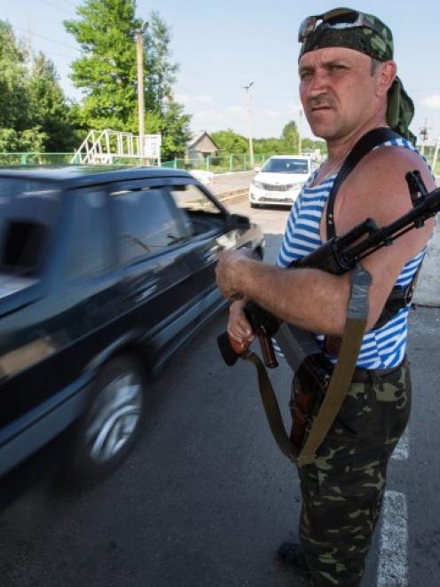 An armed pro-Russian separatist guards a border post abandoned by Ukrainian border guards at...