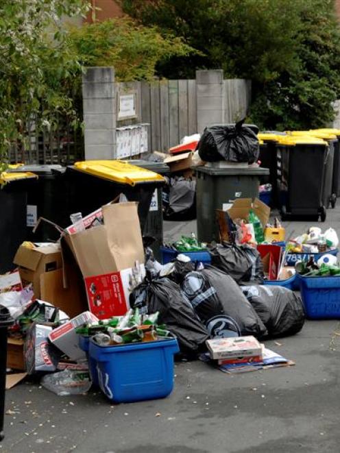 An assortment of wheelie bins, blue bins and black rubbish bags, scattered glass, cardboard and...