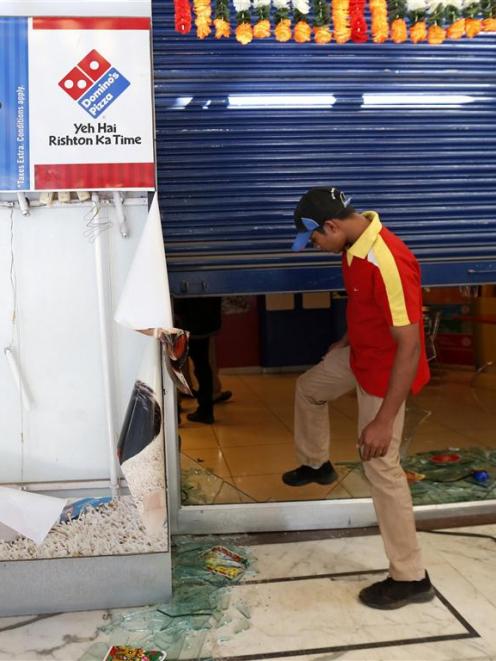 An employee enters the Dominos Pizza outlet after it was ransacked by the activists of Republican...