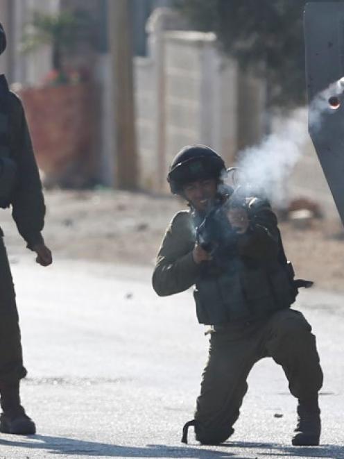 An Israeli soldier fires a tear gas canister at Palestinian protesters following a protest...