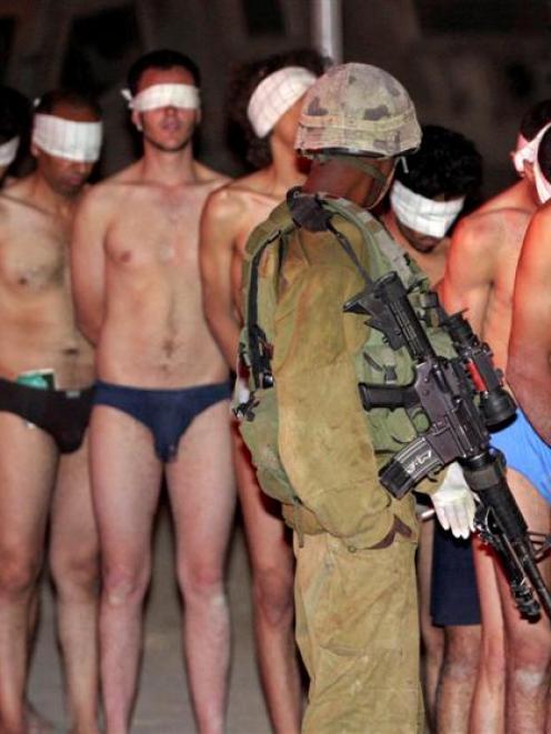 An Israeli soldier looks on, as blindfolded Palestinians, believed to be Fatah supporters who...