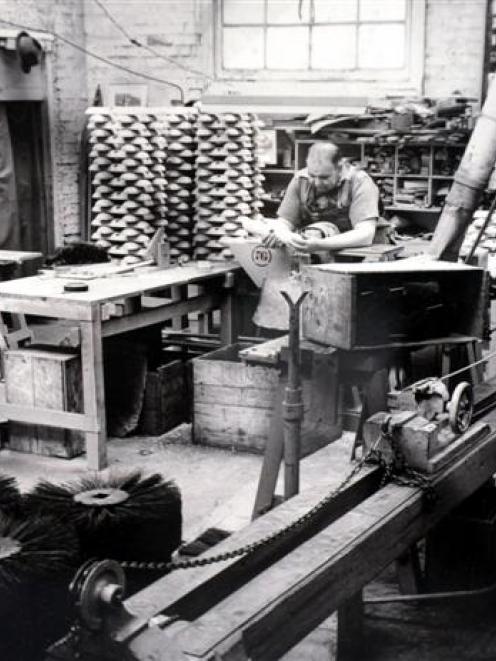 An old photograph showing production of twisted wire brushes, drilling brush stocks by hand and...