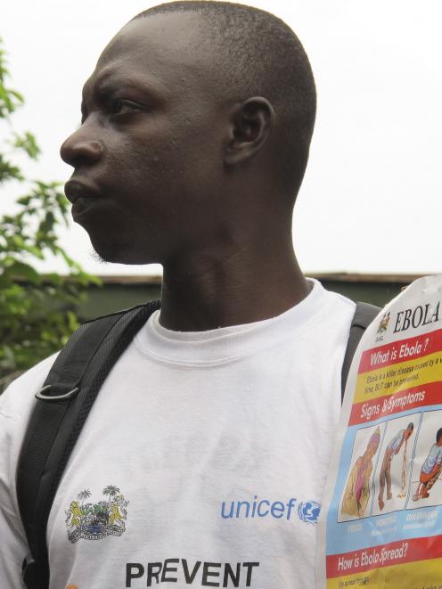 An outreach worker holds a poster bearing information on the symptoms of Ebola virus disease (EVD...