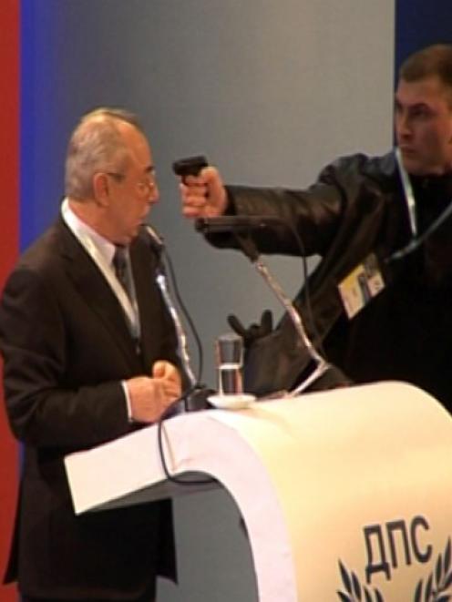 An unidentified man levels a gun at Ahmed Dogan, leader of Bulgaria's Movement for Rights and...