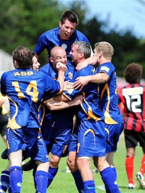 Andy Coburn leaps on top of his celebrating team-mates after Otago United scored a late winner,...