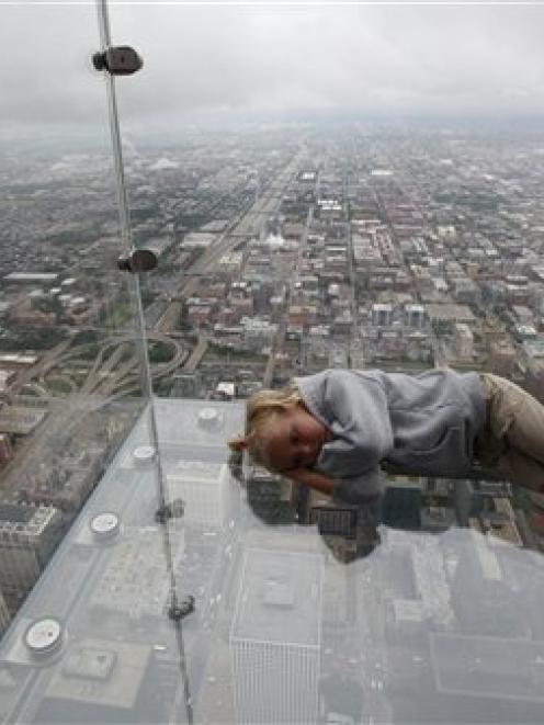 Anna Kane, 5, of Alton, Illinois, lays down on "The Ledge," the new glass balconies suspended...
