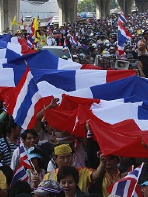 Anti-government protesters carry a large Thai national flag as they march in a rally at a major...