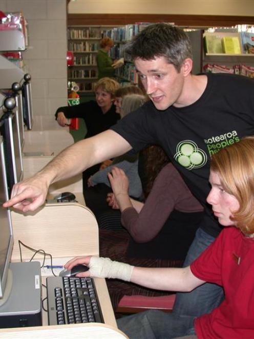 Aotearoa People's Network technical support analyst Glen Bellamy (standing) points out some of...