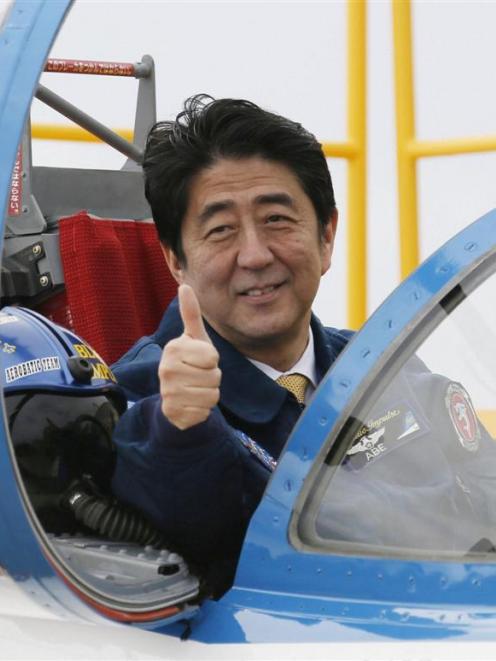 apan's Prime Minister Shinzo Abe poses inside the cockpit of a T-4  plane of the Japan Air Self...