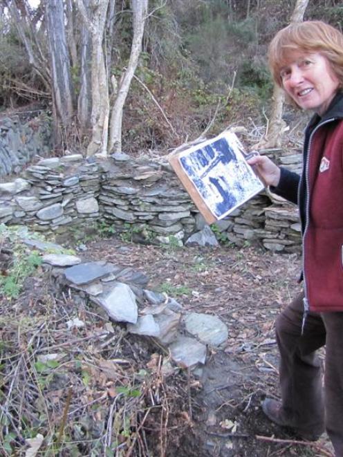 Archeological artist Jan Morrison, of Arrowtown, holds an archive picture of the stone...