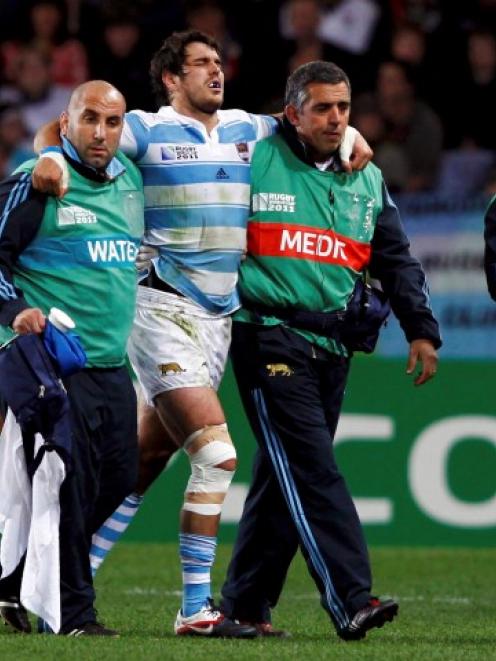 Argentina's Gonzalo Tiesi is assisted off the field during his side's Rugby World Cup Pool B...