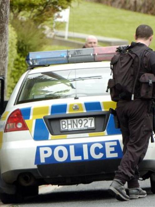 Armed offenders squad members leave a house in the Dunedin suburb of Wakari yesterday after an...