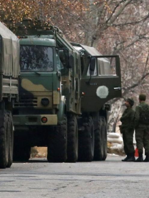 Armed people and military trucks are seen near a checkpoint outside a building on the territory...