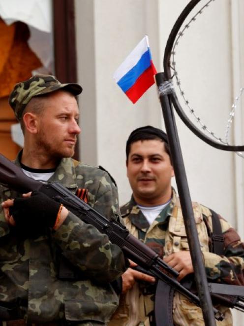 Armed pro-Russian activists stand guard at the entrance of the seized regional government...