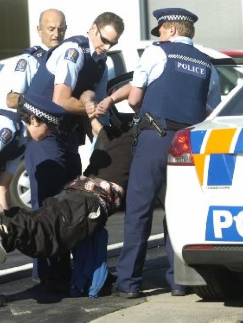 The youth is carried in handcuffs to a police car by (from left) Constable Louise Pearce,...