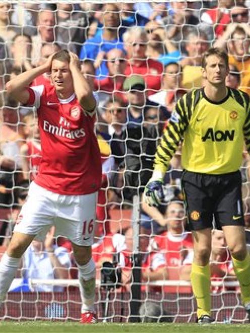 Arsenal's Aaron Ramsey, watched by Manchester United keeper Edwin Van der Sar, reacts after...