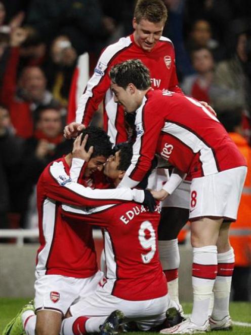 Arsenal's Eduardo, seated centre, kisses teammate Carlos Alberto Vela, seated left, after scoring...