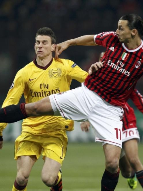 Arsenal's Laurent Koscielny (L) and AC Milan's Zlatan Ibrahimovic fight for the ball during their...