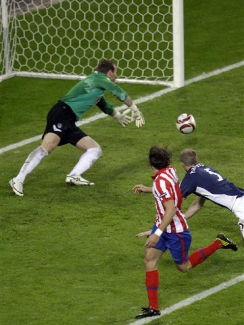 Atletico's Diego Forlan, foreground, scores his side's second goal during the soccer Europa...