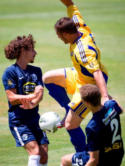 Auckland City FC's Albert Riera (left) and Simon Arms clash with Otago United's Victor Da Costa...