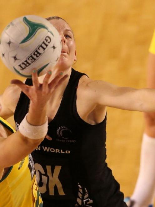 Australia's Caitlin Bassett receives the ball despite the efforts of New Zealand's Katrina Grant....