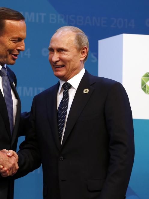 Australian Prime Minister Tony Abbott (L) shakes hands with Russian President Vladimir Putin as...