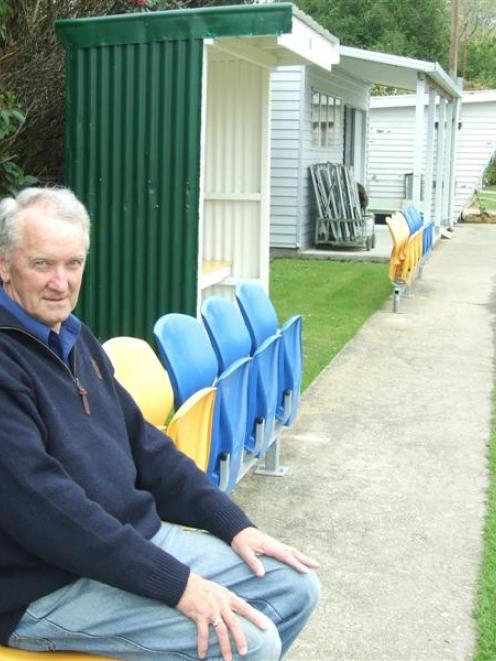 Balclutha Bowling Club secretary Graham Dale sits on a row of  salvaged plastic Carisbrook seats...