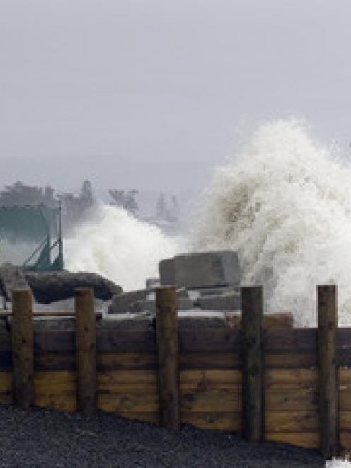 Residents watch waves crash into walls at Haumoana yesterday.