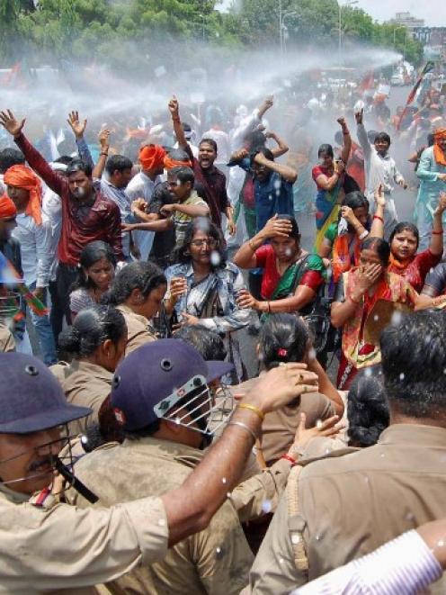 Bharatiya Janata Party supporters shout slogans as police use a water cannon to stop them from...