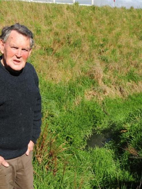 Blanket Bay resident Gerry Boyle stands beside a ditch where septic tank run-off has accumulated...