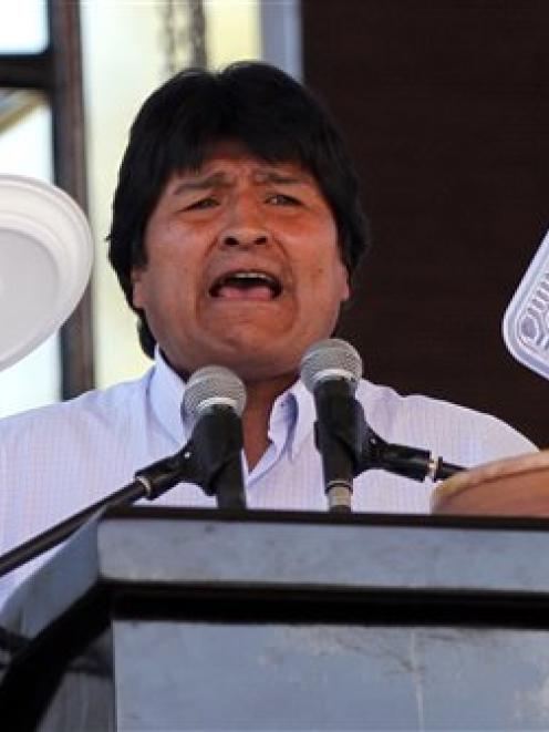 Bolivia's President Evo Morales holds up plates made of plastic as he speaks at the World People...