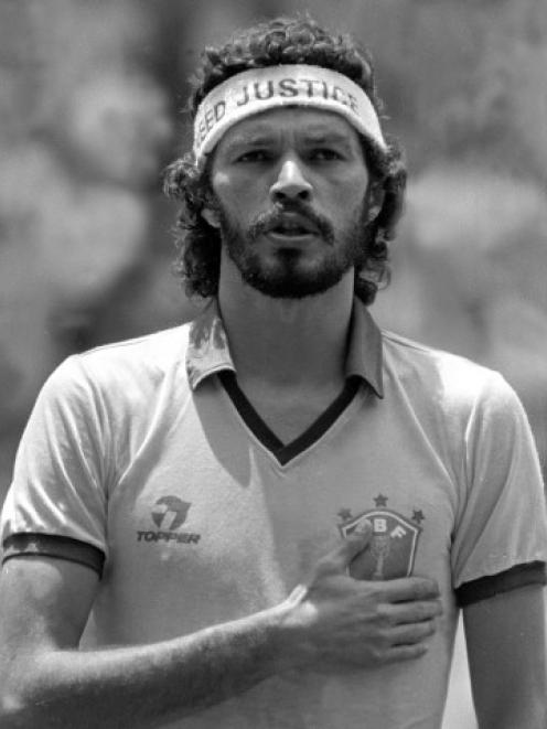 Brazilian midfielder Socrates Oliveira holds his hand over the emblem of his jersey while Brazil...