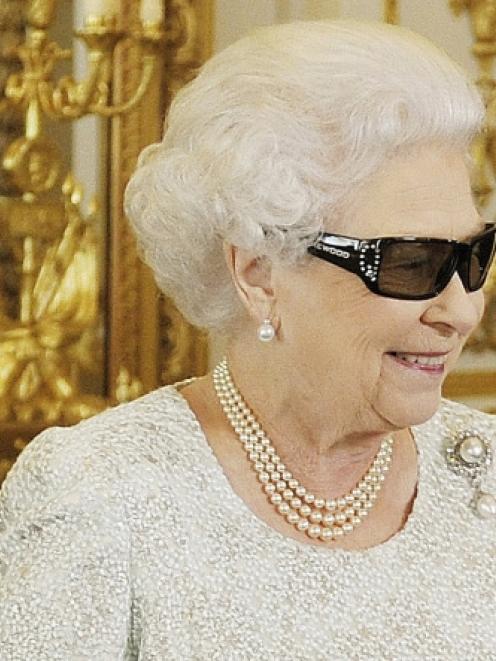 Britain's Queen Elizabeth watches a preview of her Christmas message with a pair of 3D glasses,...